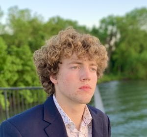 Man with curly hair looks into distance.