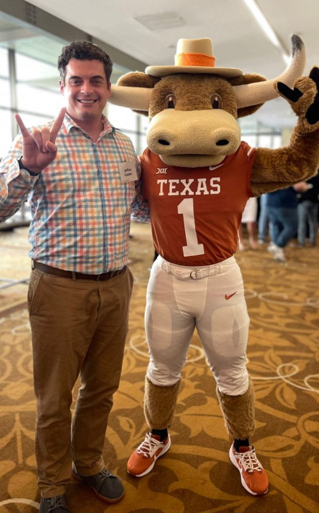 Jeffrey standing with Hook 'Em, our mascot. 