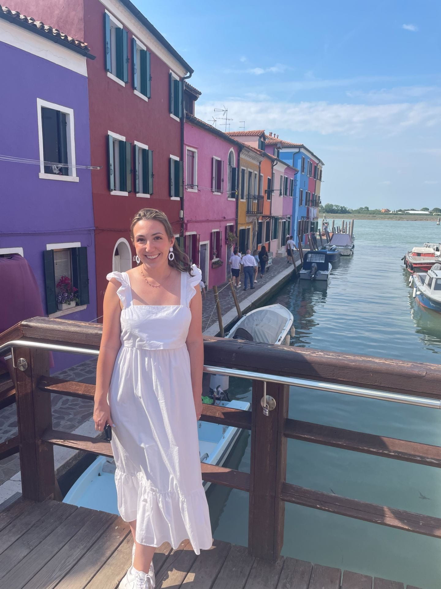 Marion Krueger, Evening MBA '25 poses in front of colorful houses lining a lake. 